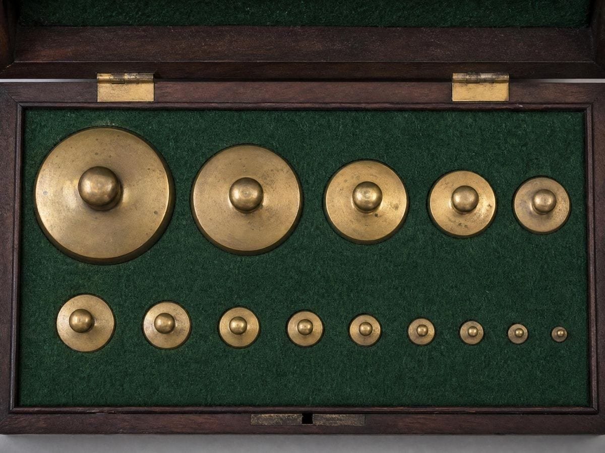 Brass balance weights stepping from large to small in a felt-lined fitted case