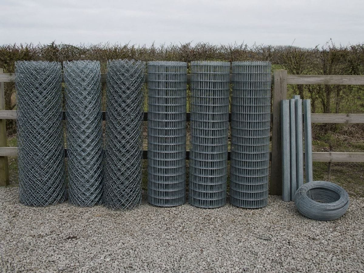 A fencing yard with rolls of galvanised mesh standing on end, cut ends toward camera