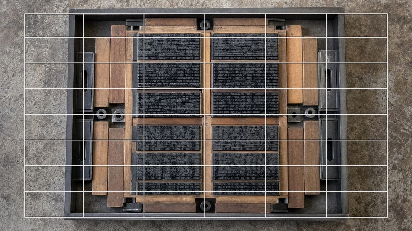 Layout grid overlay on a locked letterpress forme, type blocks divided by wooden furniture