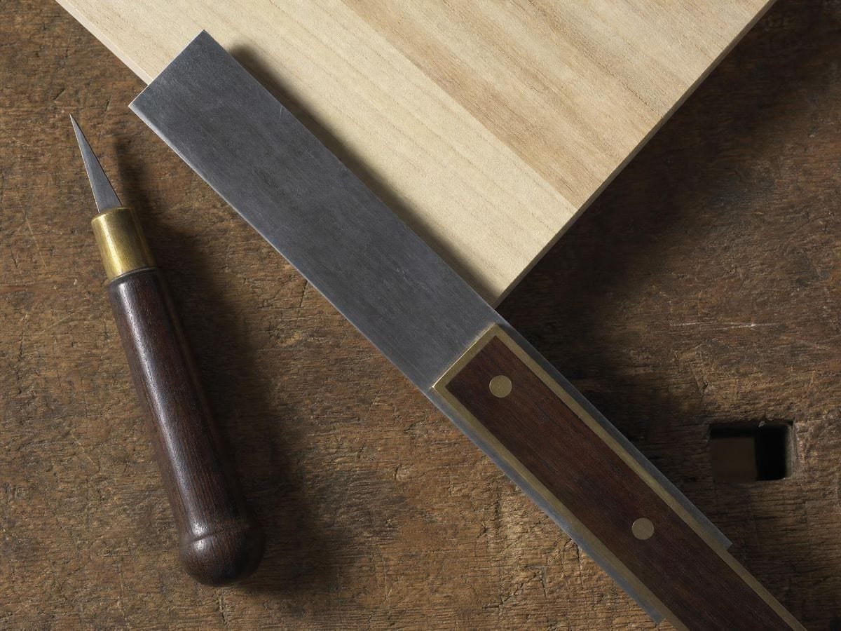 A steel and rosewood mitre square laid at forty-five degrees across a timber corner