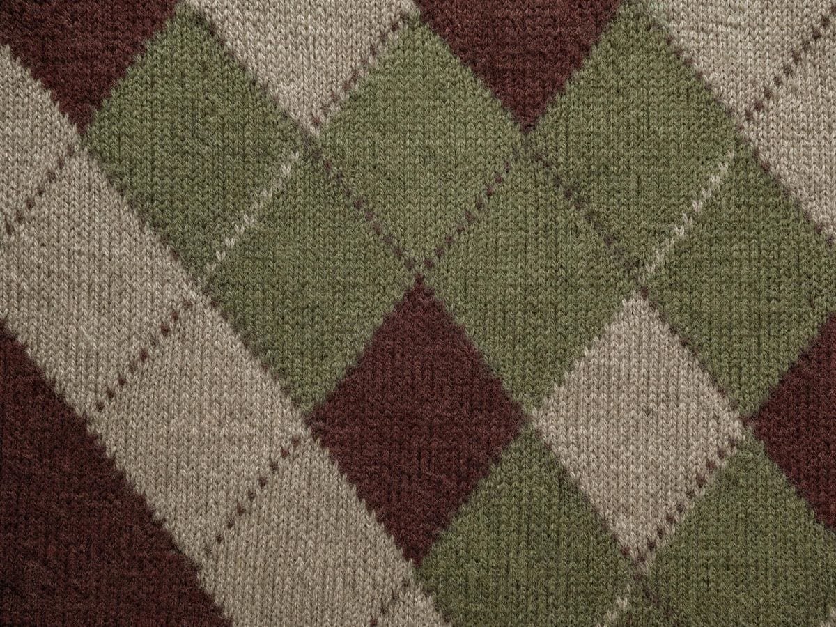 A hand-knitted argyle swatch of lozenges meeting point to point in muted wool