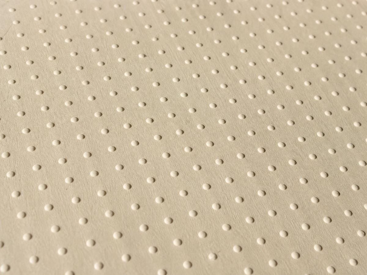 Regular embossed dots raised in even cells across a sheet of heavy cream manila