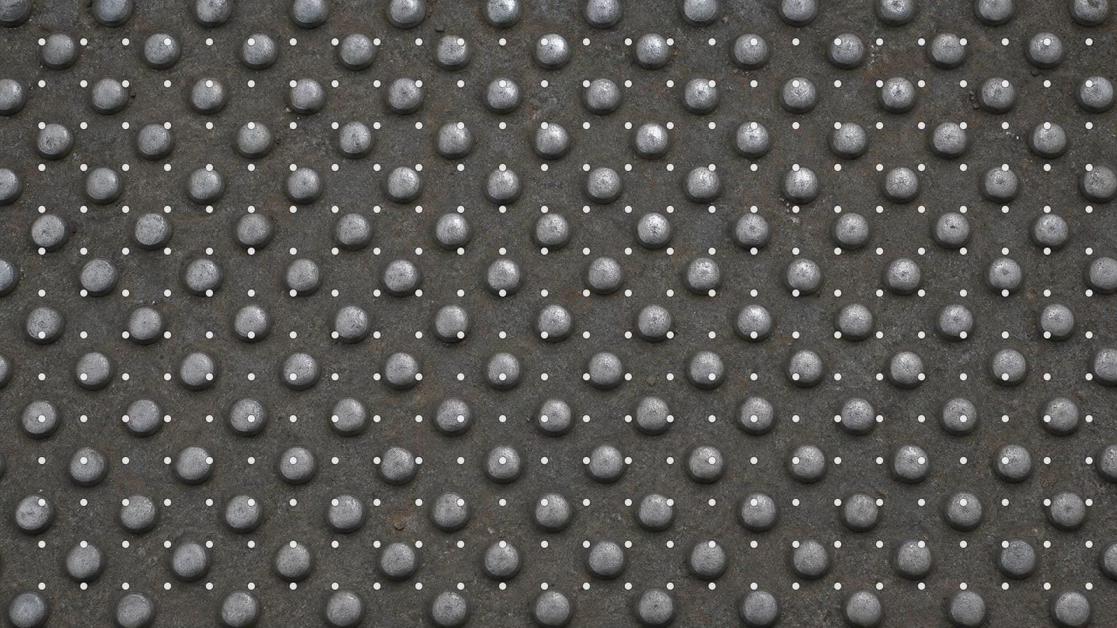 Dot grid overlay on a worn steel floor plate of evenly spaced polished studs
