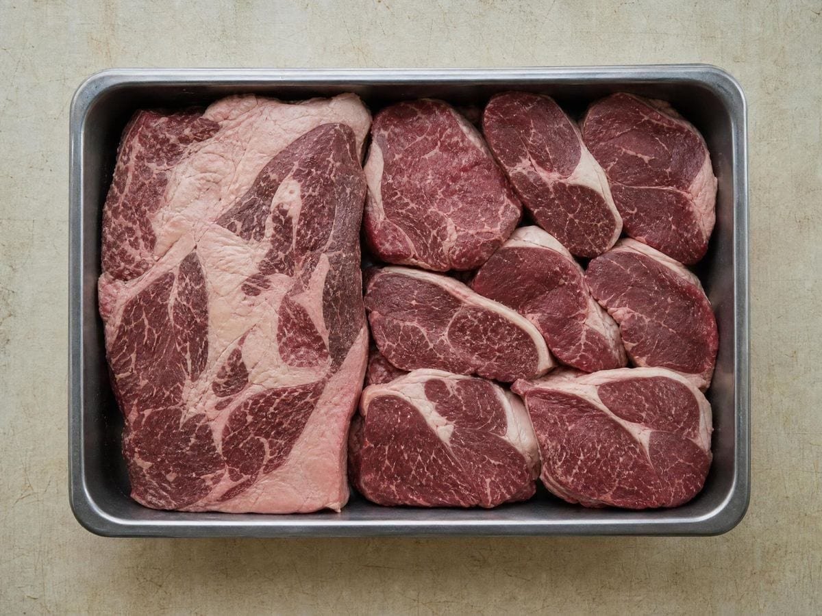 A stainless tray holding trimmed cuts of several sizes fitted together to fill it