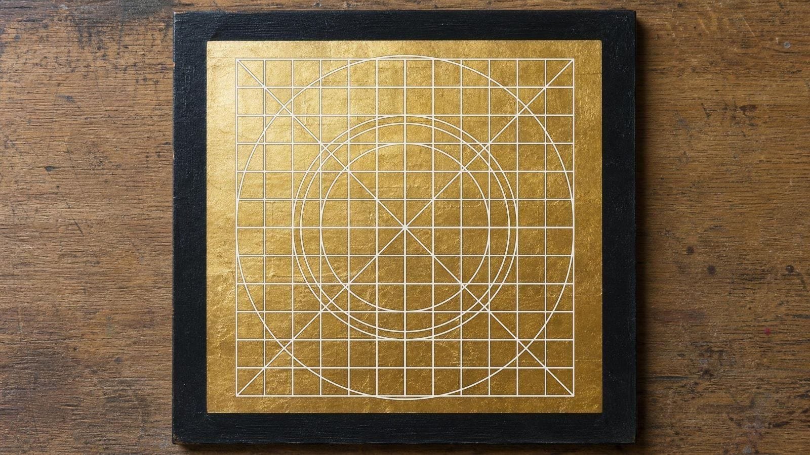 Logo construction grid overlay on a blank gilded signwriter panel of overlapping leaf squares