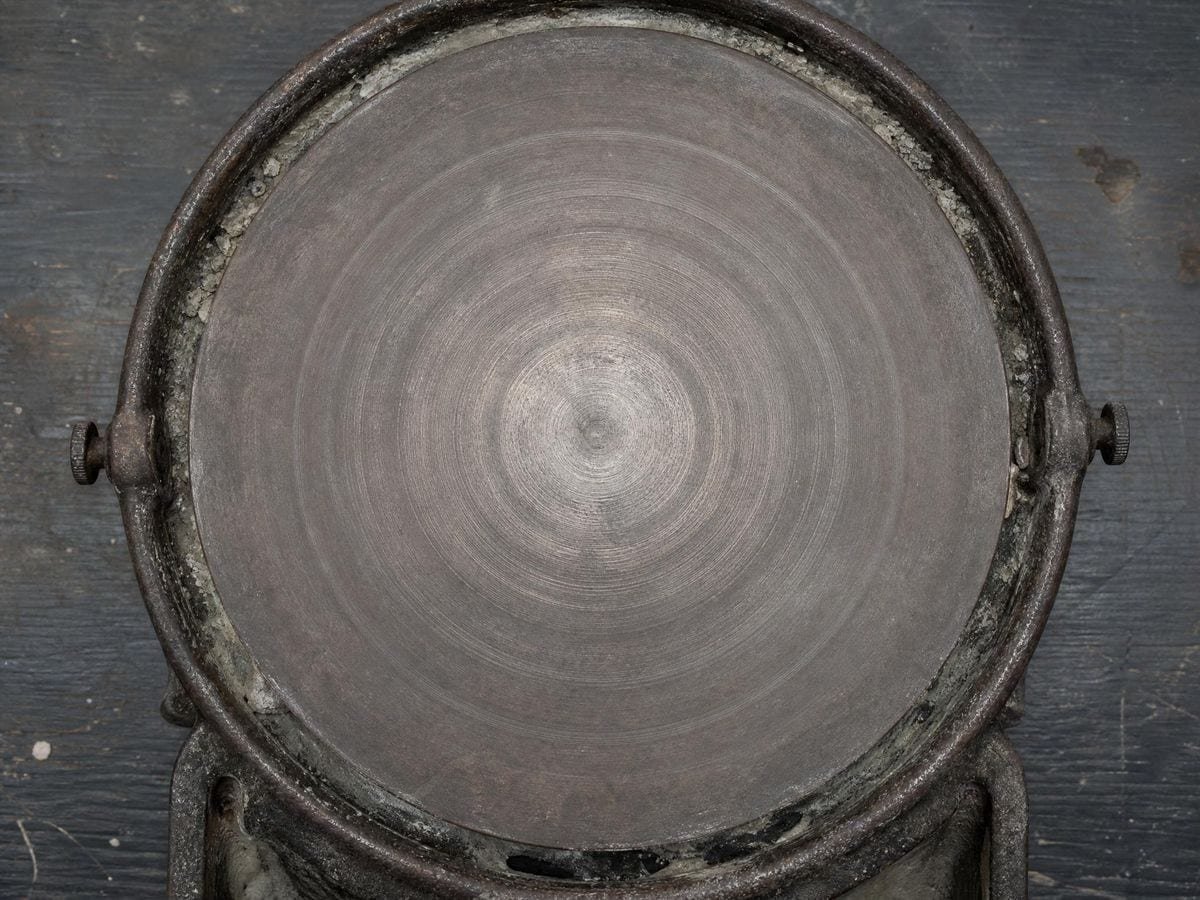 An empty cast-iron banding wheel with faint concentric traces worn into its disc
