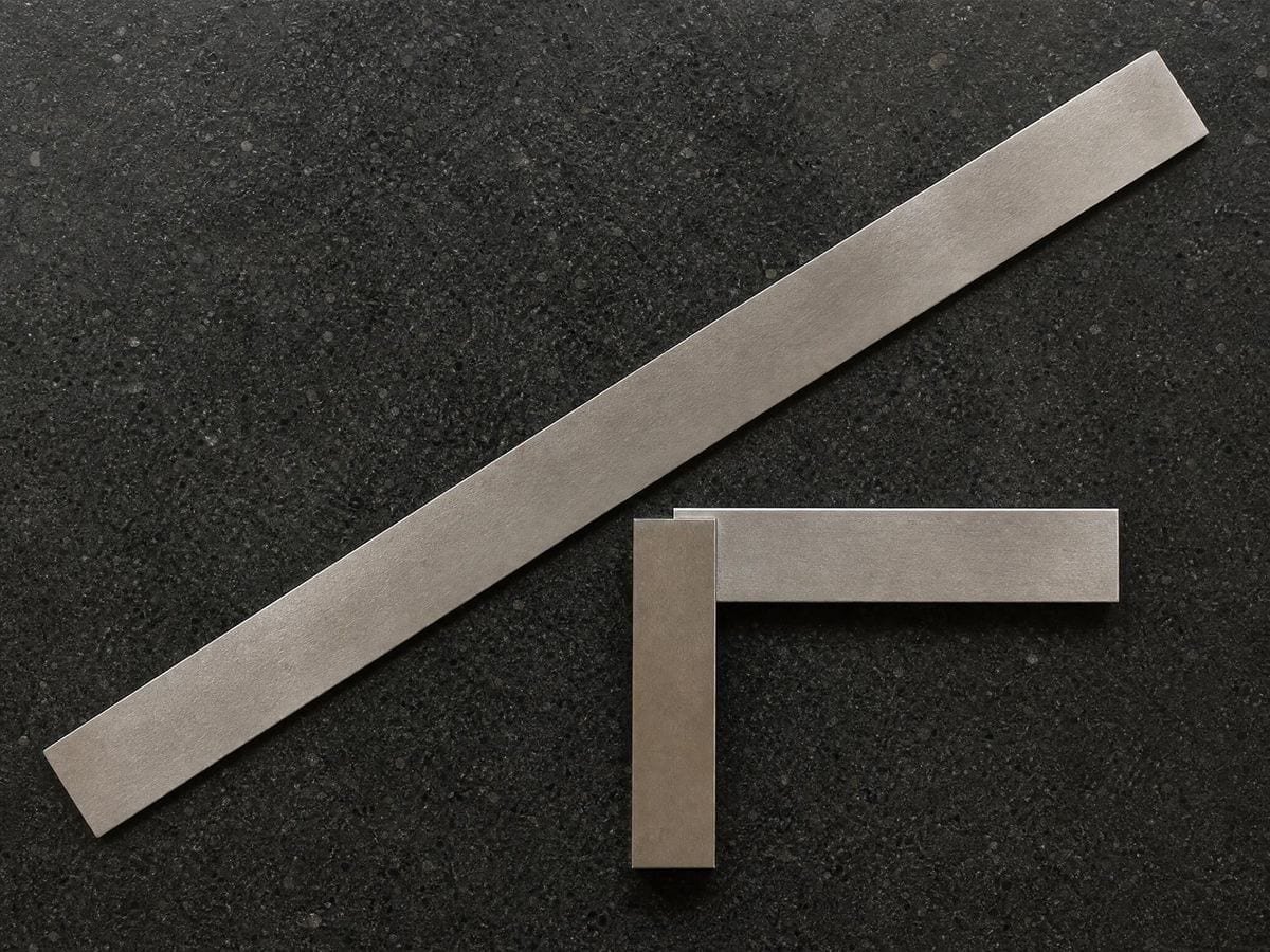 A ground steel rule and small engineer's square lying on a black granite surface plate