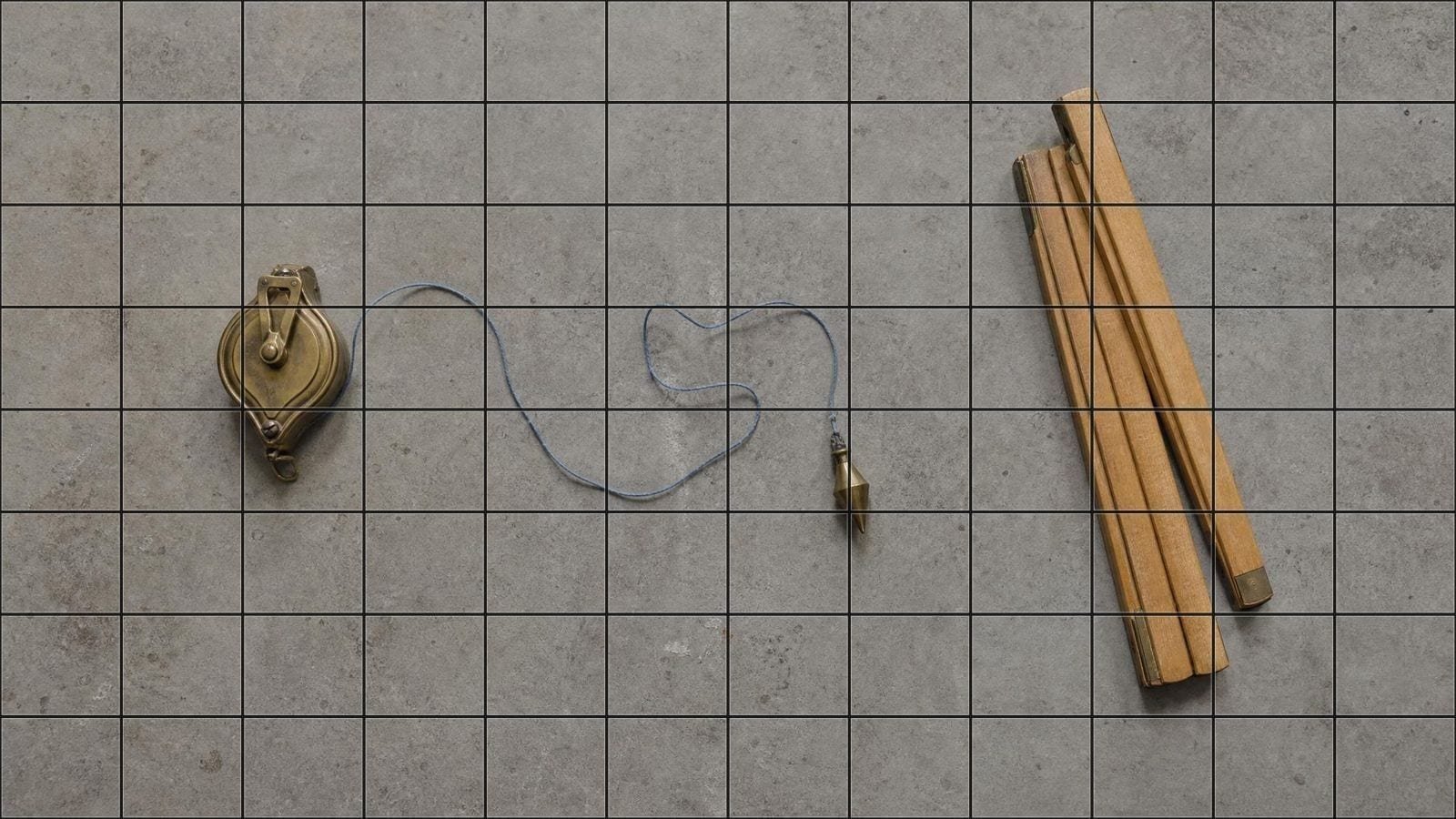 Mural scaling overlay on a chalk line reel, plumb bob and boxwood rule on a bare slab