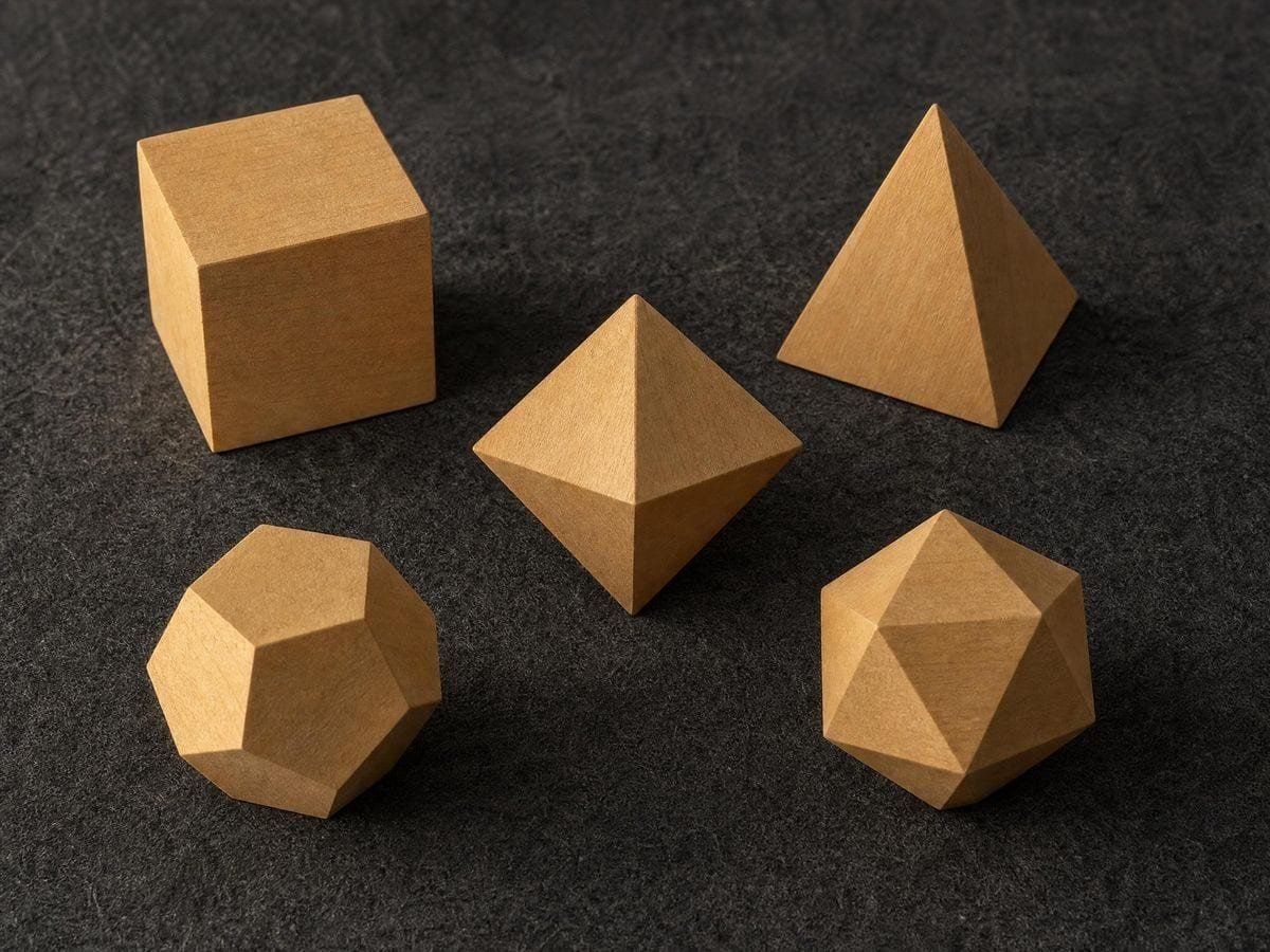 Five hand-carved boxwood polyhedra with cleanly cut facets on dark wool cloth
