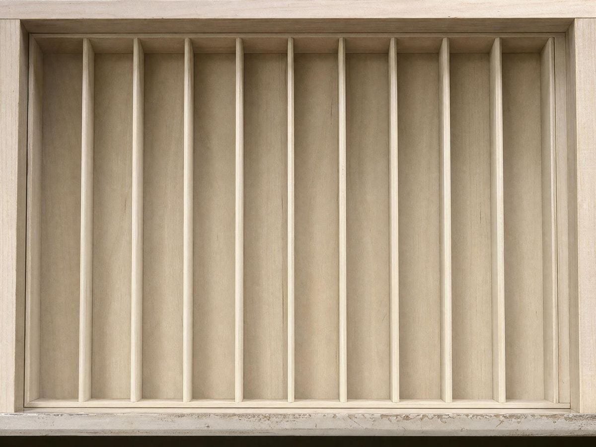 A shallow drawer divided into narrow empty vertical bays by thin timber partitions